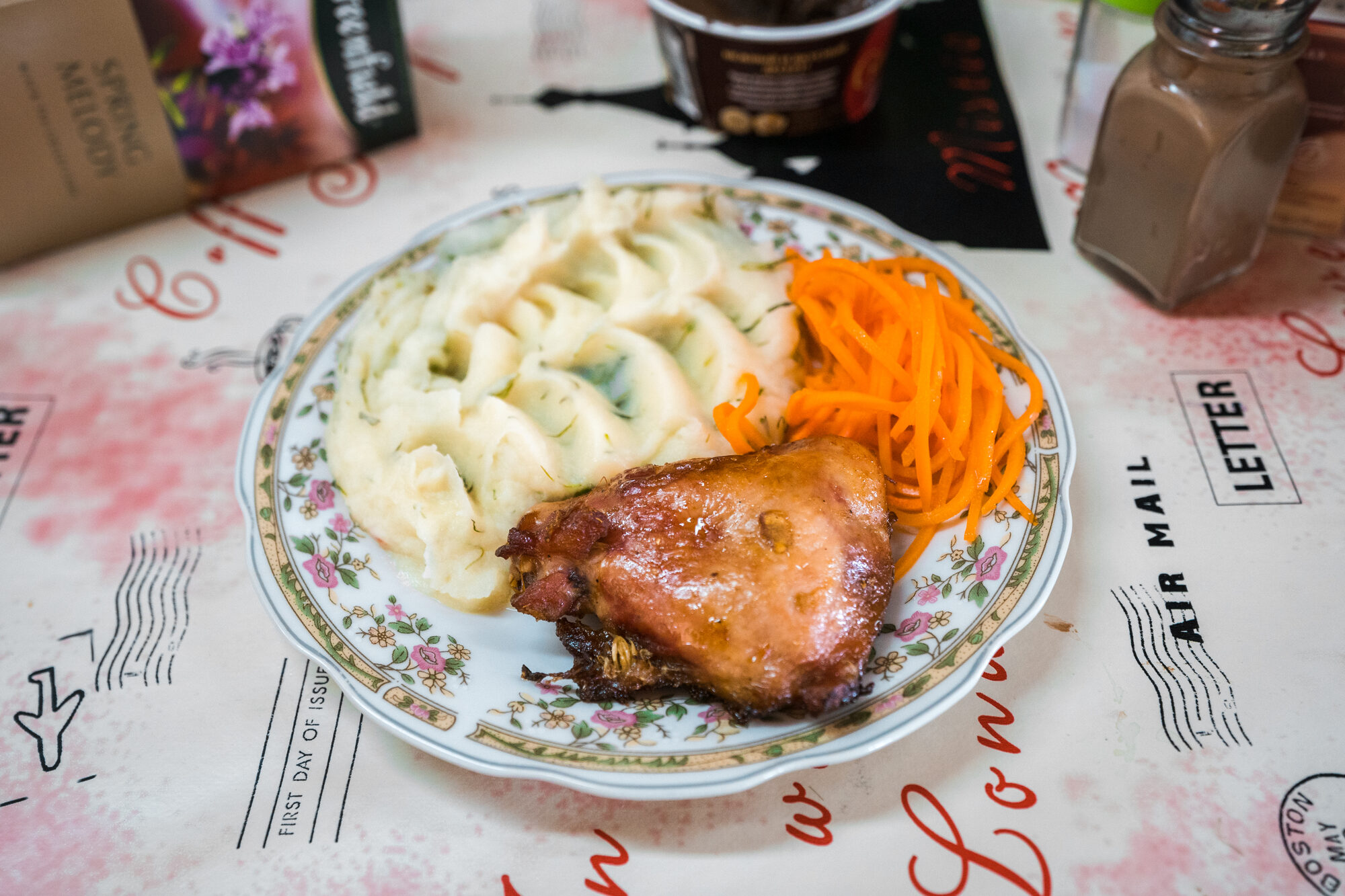 Chicken and mashed potatoes with carrot salad on a flowered plate at base camp