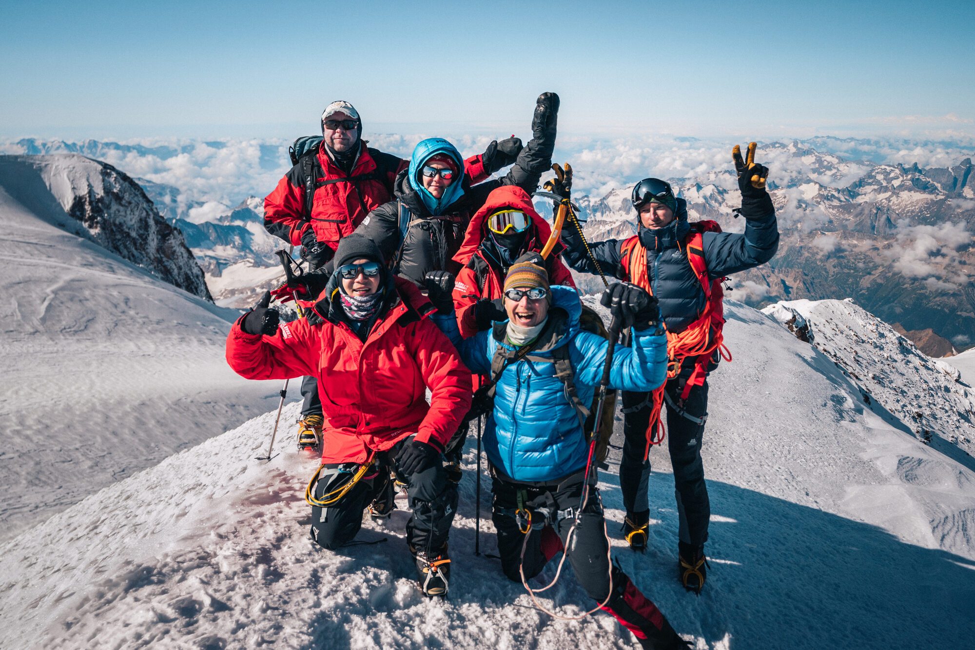 Full climbing team celebrating at the summit of Elbrus with arms raised