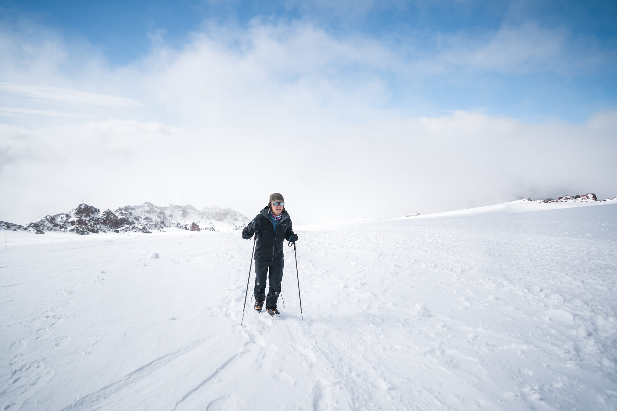 Grace hiking through deep snow with trekking poles on Elbrus