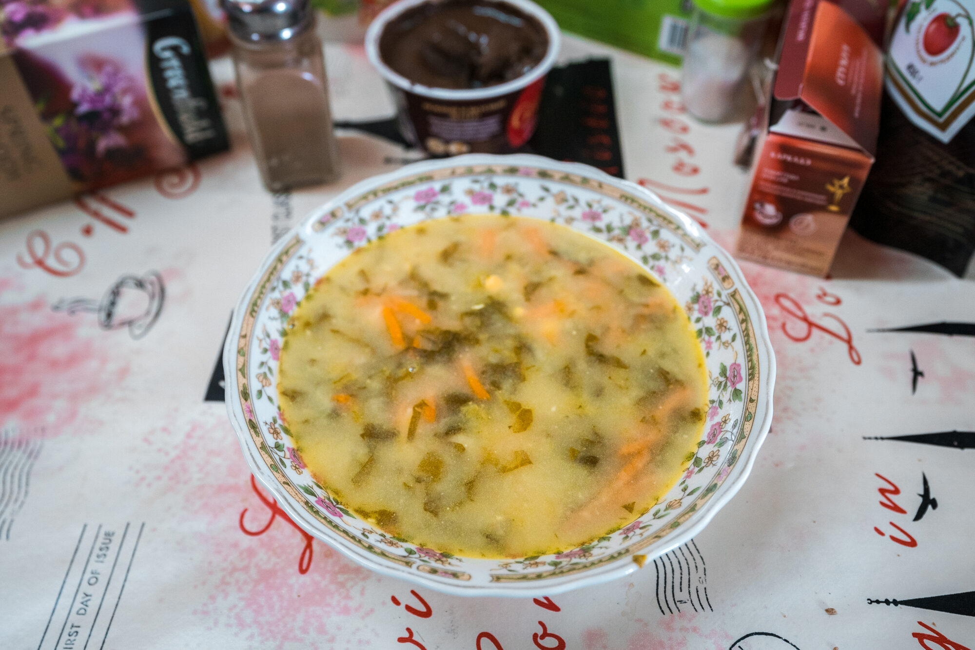 Bowl of vegetable soup on a flowered plate at the base camp dining table