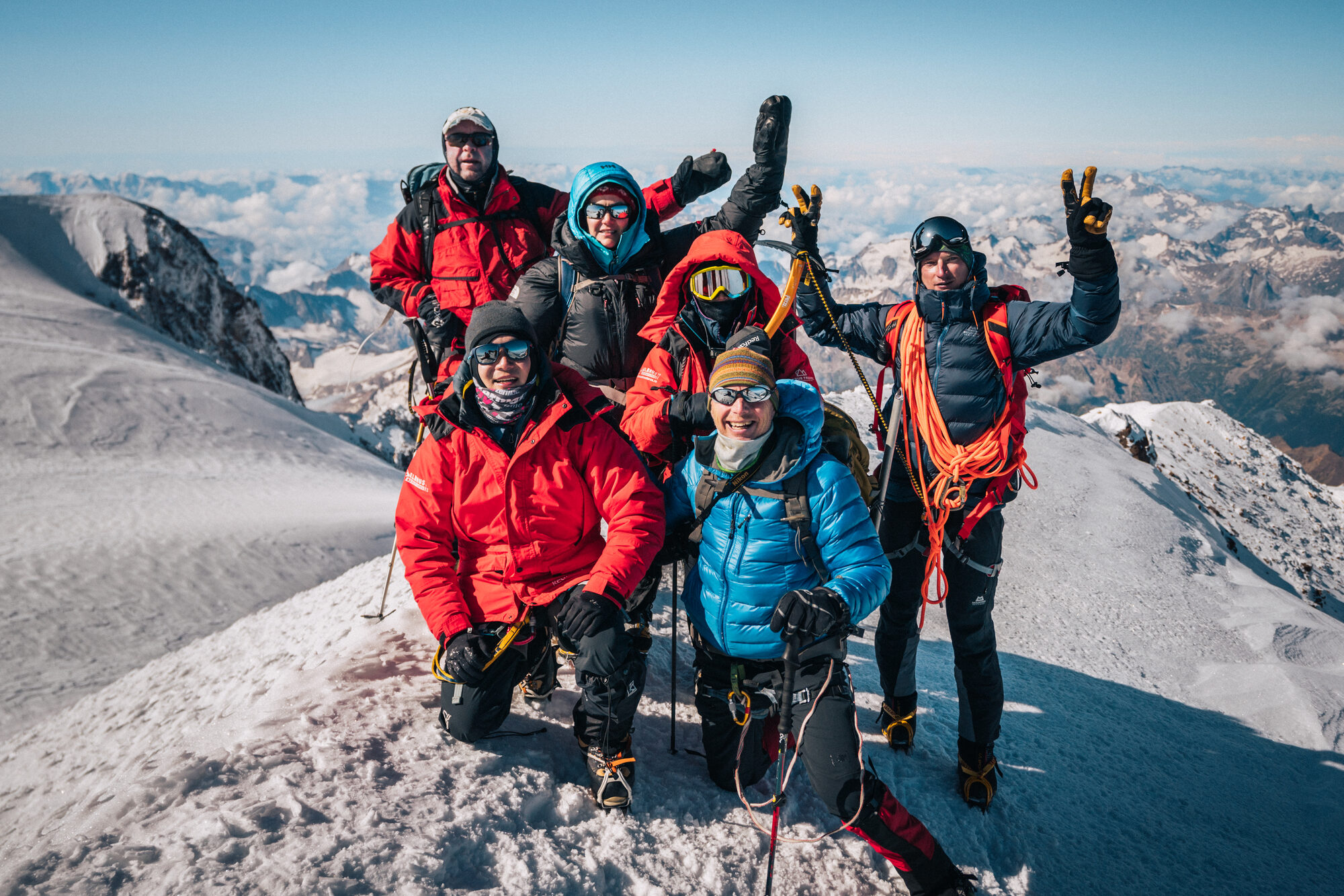 Team with arms raised celebrating on the summit of Mount Elbrus