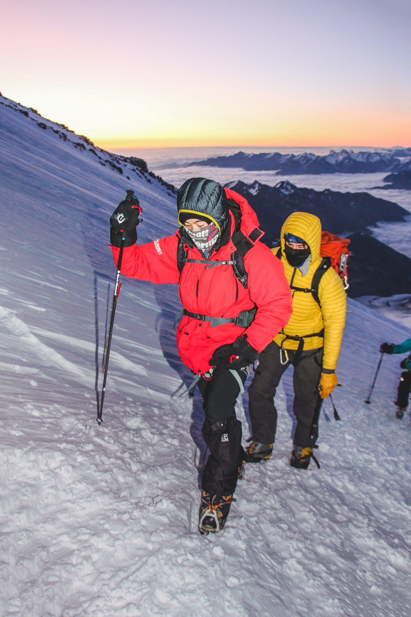 Climbers ascending Elbrus at sunrise with alpenglow and Caucasus panorama