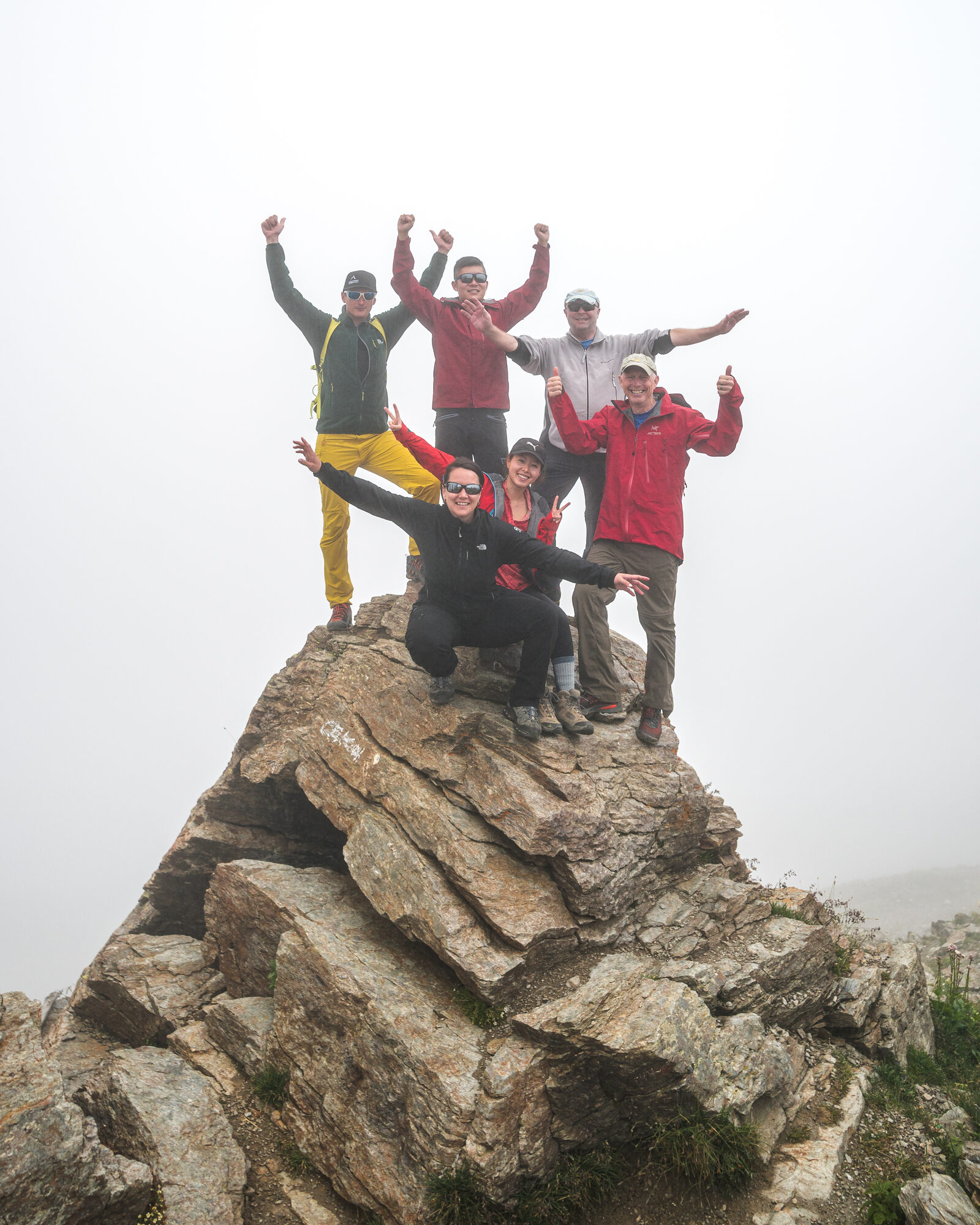 Team celebrating near the top of Mount Cheget with Elbrus hidden in cloud behind them