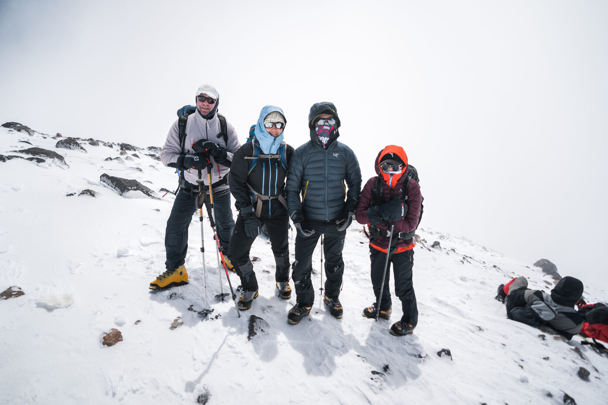 Four climbers posing together on the snowy slopes of Elbrus in foggy conditions