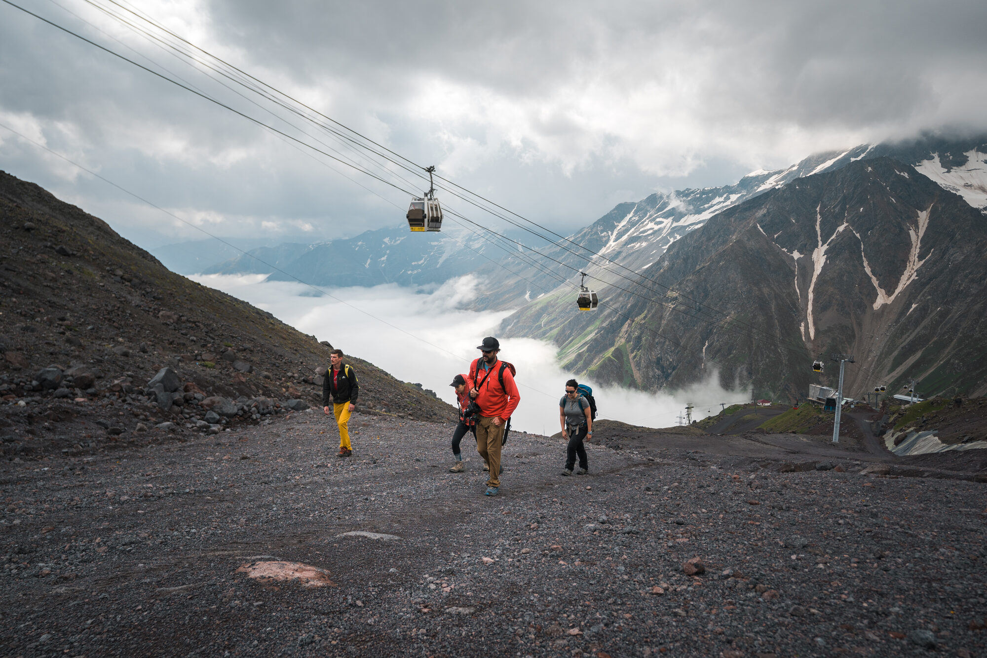 Hikers on the gravel slopes of Elbrus with mountains behind