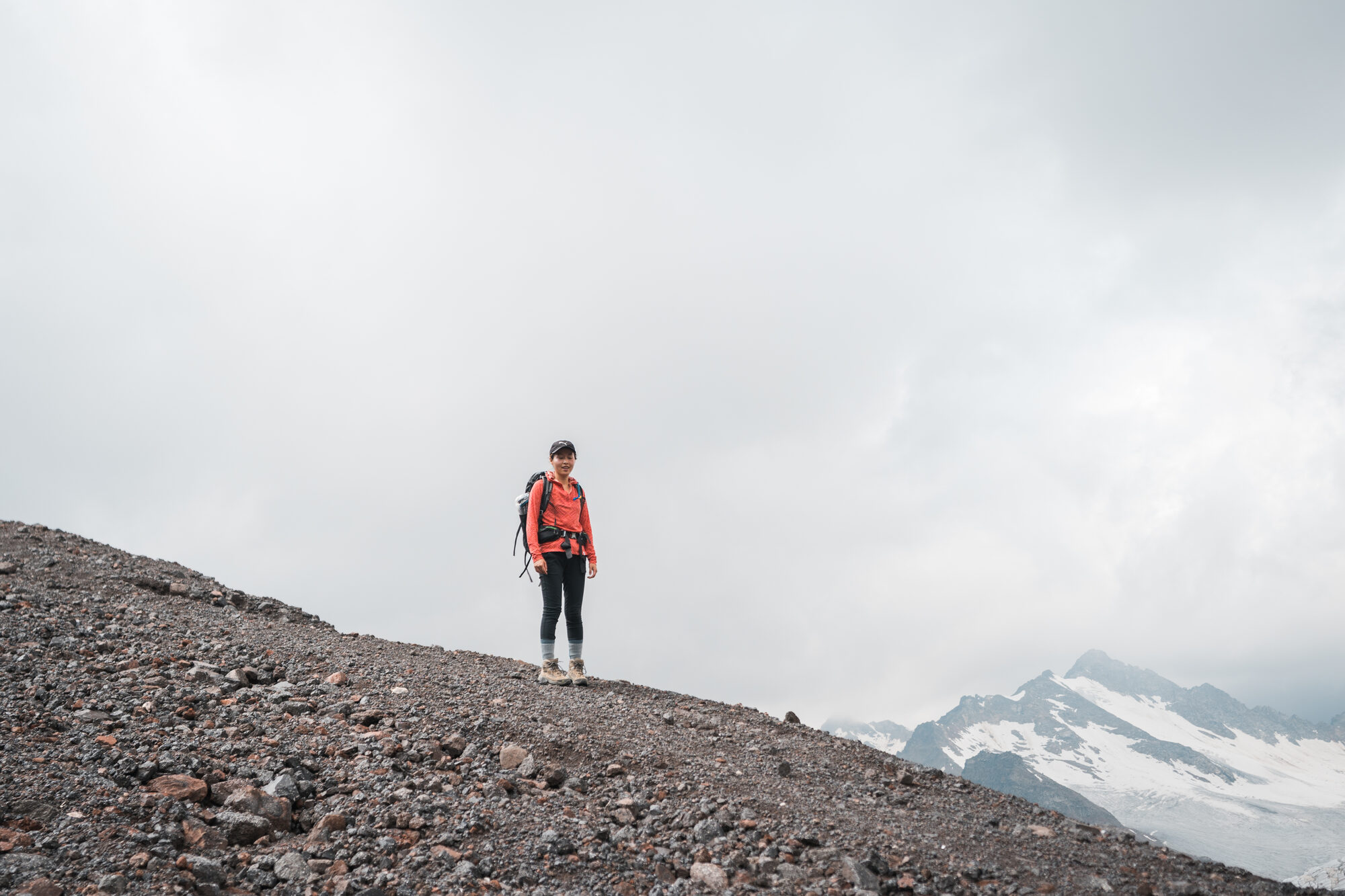 Climber pausing on a gravel ridge above the glacier on Elbrus's lower slopes