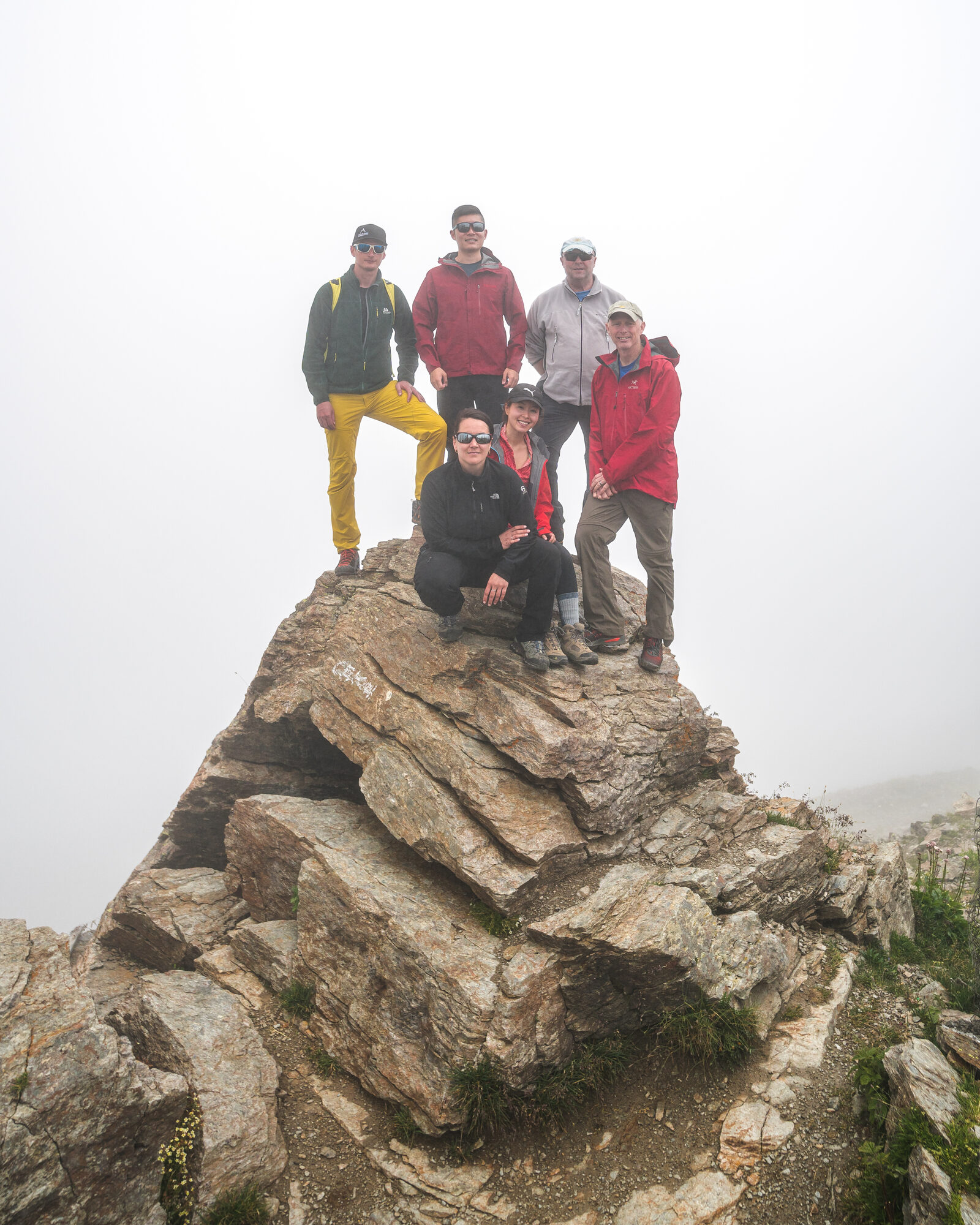 Team posing on the rocky summit of Cheget Peak in fog