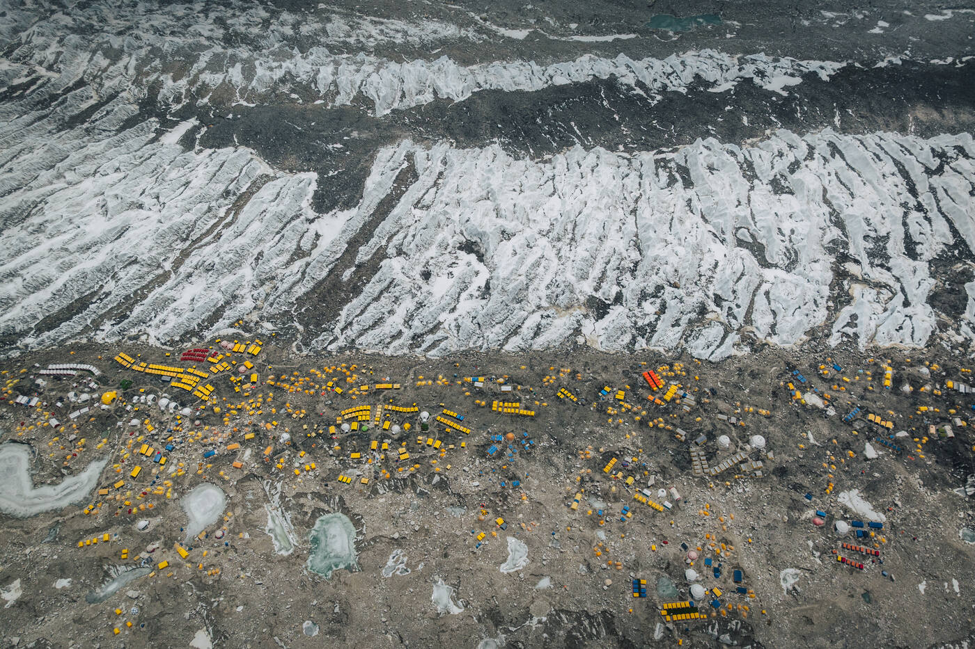 Aerial view of Base Camp tents lined along the moraine beside the wave-like ice of the Khumbu Glacier