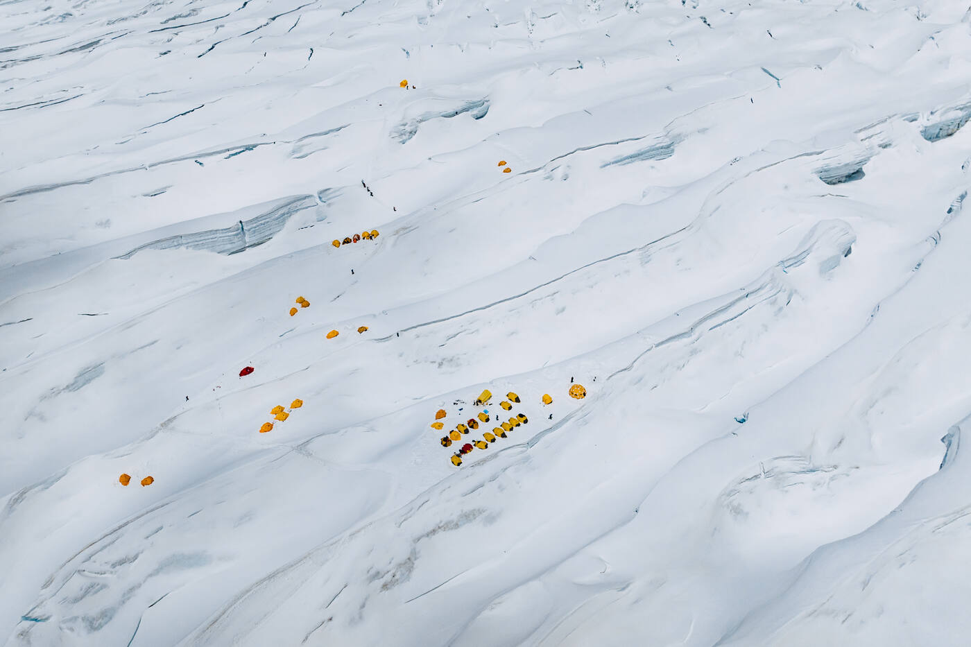 Aerial view of tents scattered across the crevassed snow of Camp 1