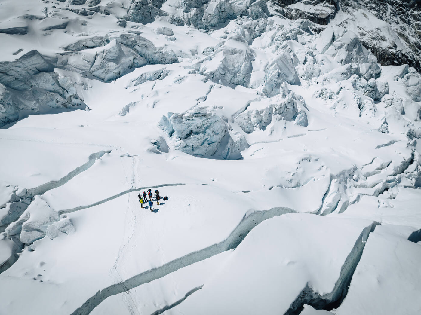 Aerial view of a group of climbers crossing a heavily crevassed snowfield