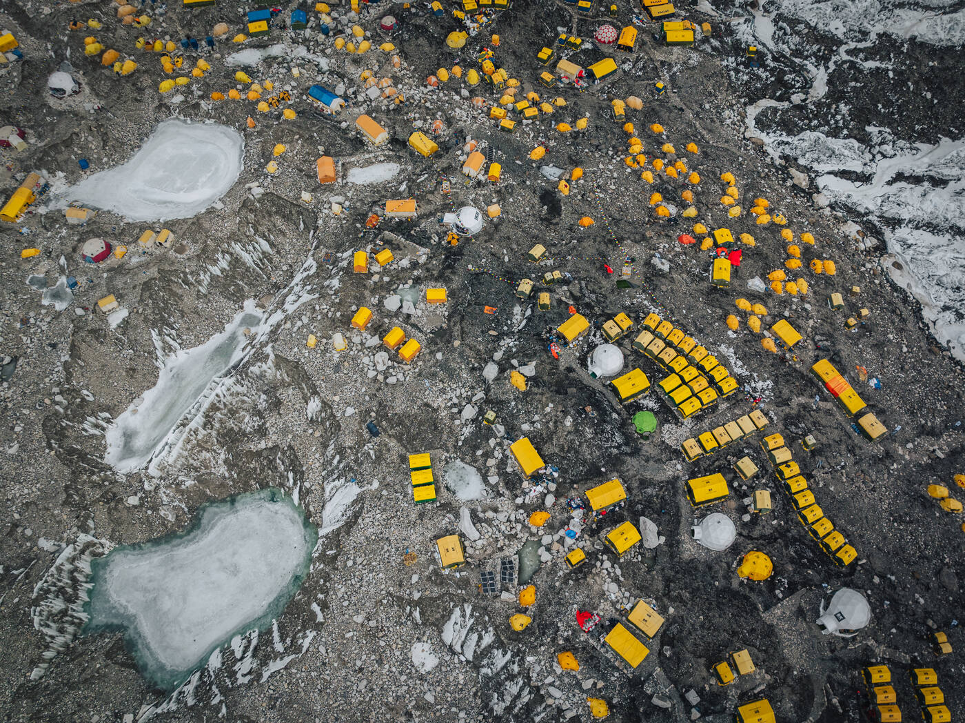 Aerial drone photo showing hundreds of yellow and colored tents spread across the Khumbu Glacier at Everest Base Camp