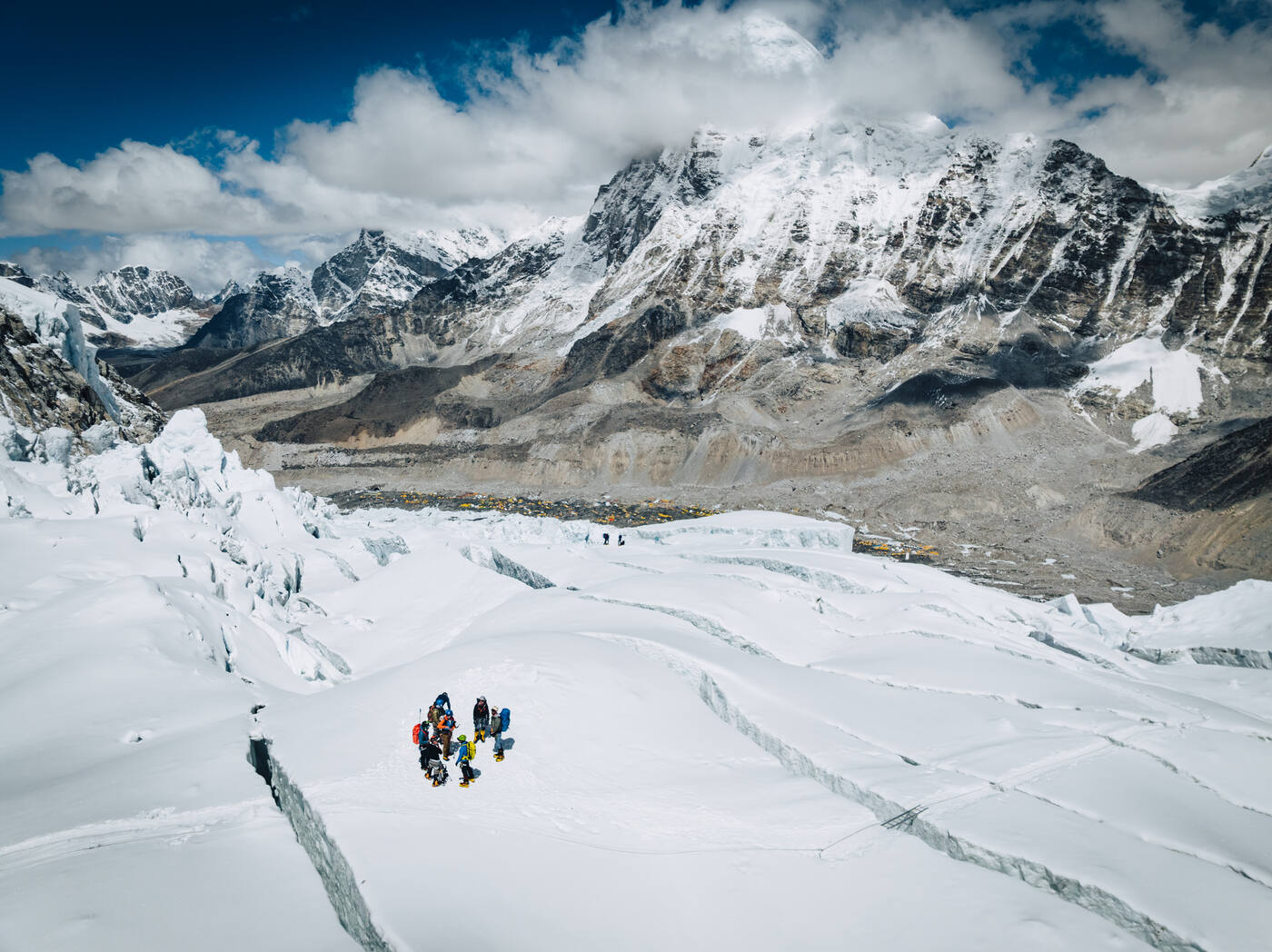 A group of climbers on the glacier below the Icefall with peaks and Base Camp behind