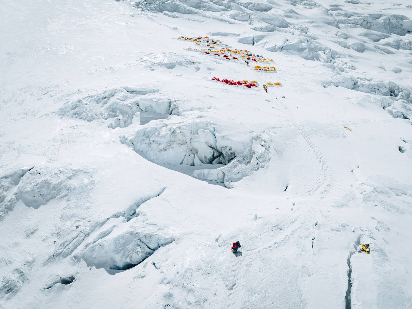 Aerial view of tents on the crevassed slope of the Lhotse Face with climbers below