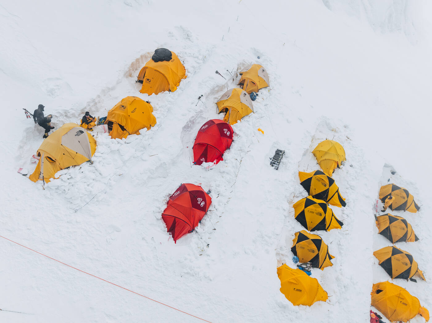 Aerial close view of yellow and red tents pitched in snow
