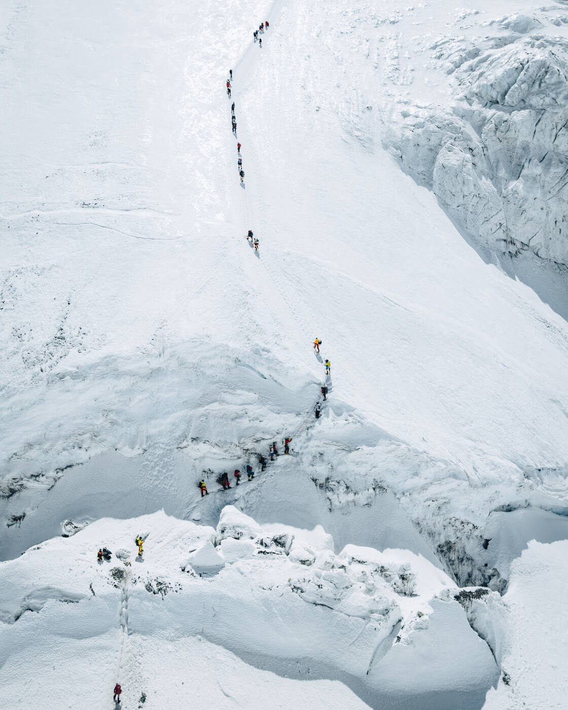 Aerial view of a line of climbers ascending a snow slope