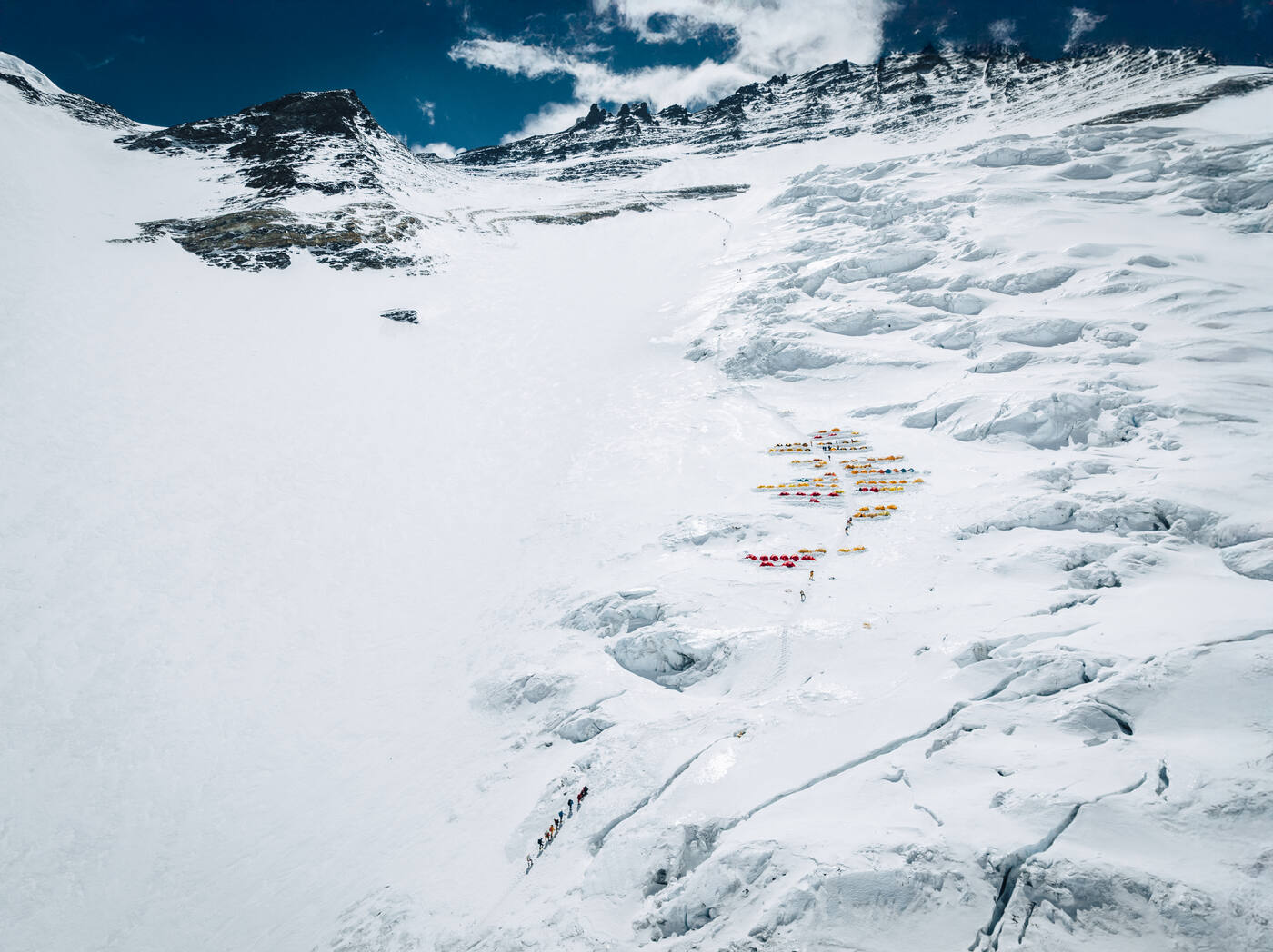 Aerial view of a cluster of tents high on the snow of the Lhotse Face