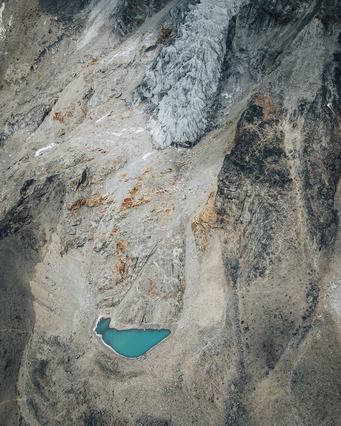 Aerial view of a turquoise glacial lake in rocky terrain