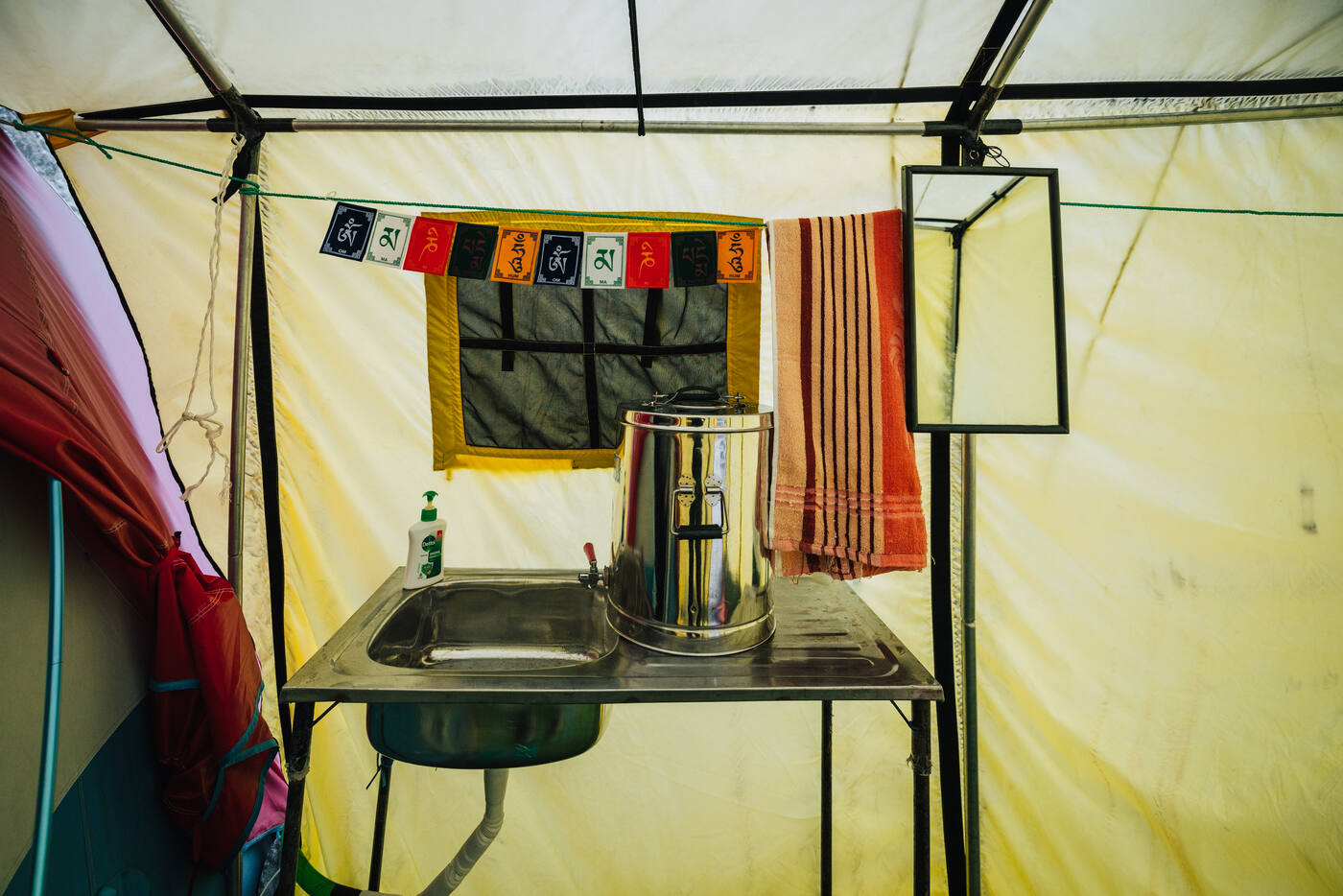 Interior of the wash tent at Everest Base Camp with sink, kettle, and prayer flags