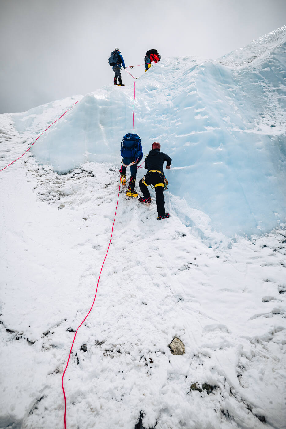 Climbers ascending steep blue ice wall on fixed ropes near the Khumbu Icefall