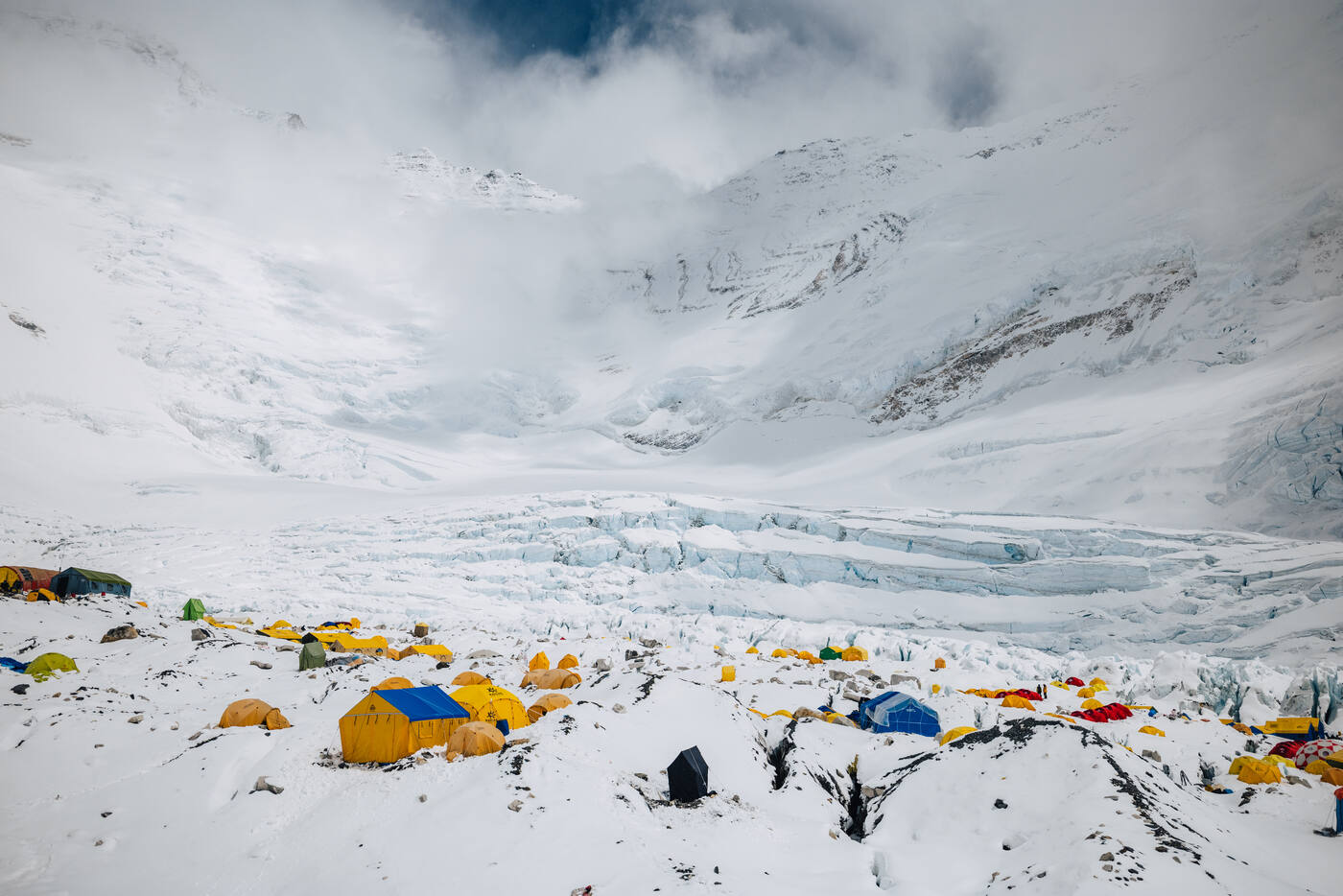 Colorful tents at Camp 2 on the rocky moraine with the Lhotse Face rising into cloud behind