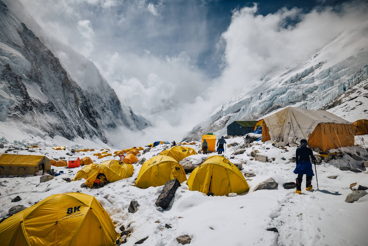 Yellow tents and the mess tent at Camp 2 on the moraine with cloud-covered walls above