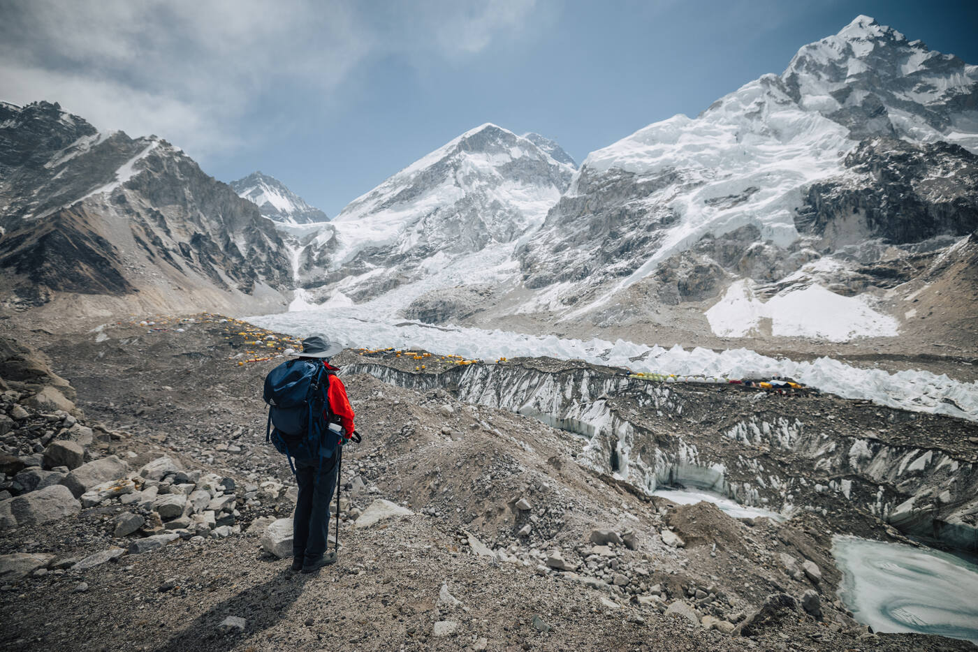 Climber walking across glacial moraine toward the Khumbu Icefall and snow-covered peaks