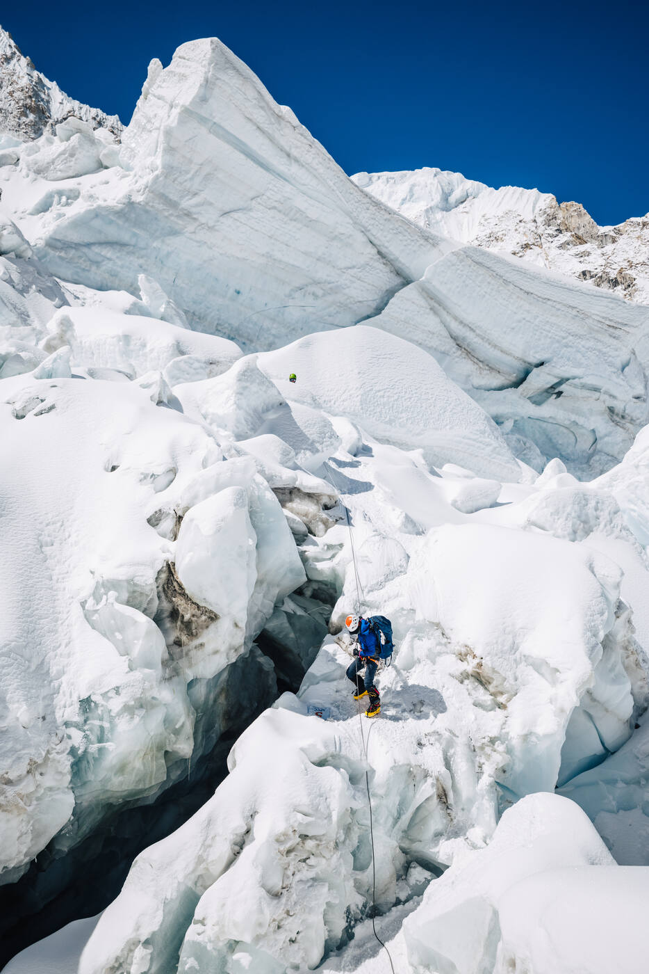 Climber navigating among large ice seracs in the Khumbu Icefall