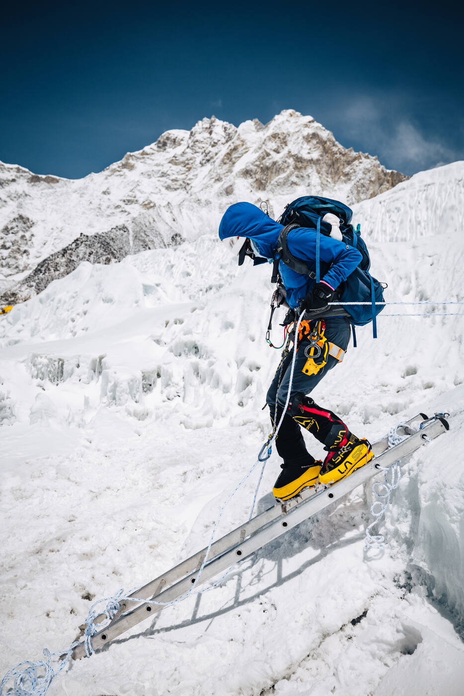 Climber crossing a ladder over ice in the Khumbu Icefall