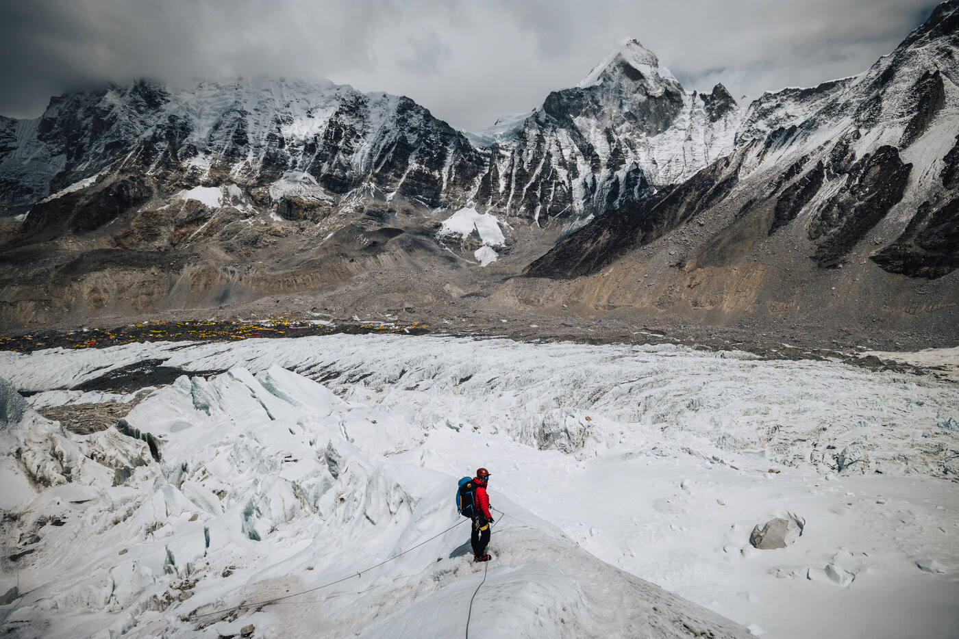 A climber in red standing in the lower Icefall looking down over Base Camp and the glacier