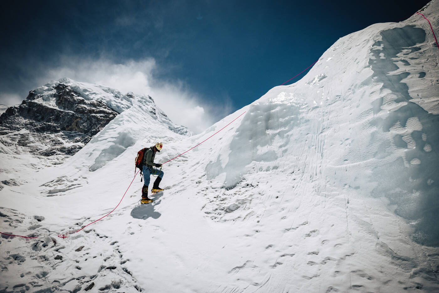 Climber descending on rope between two massive ice walls in the Khumbu Icefall