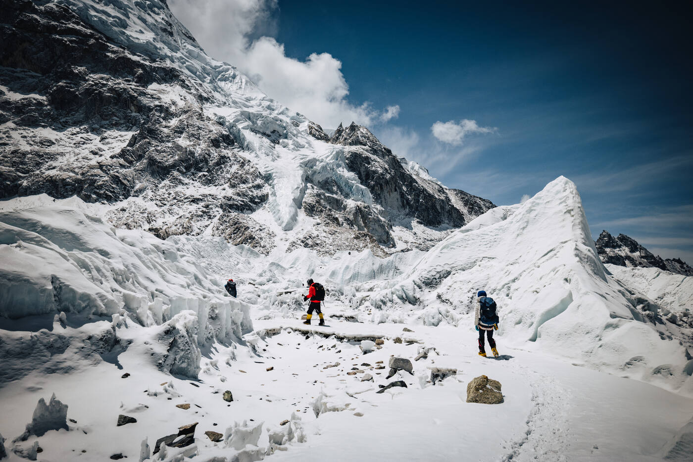 Two climbers navigating between massive ice seracs in the Khumbu Icefall