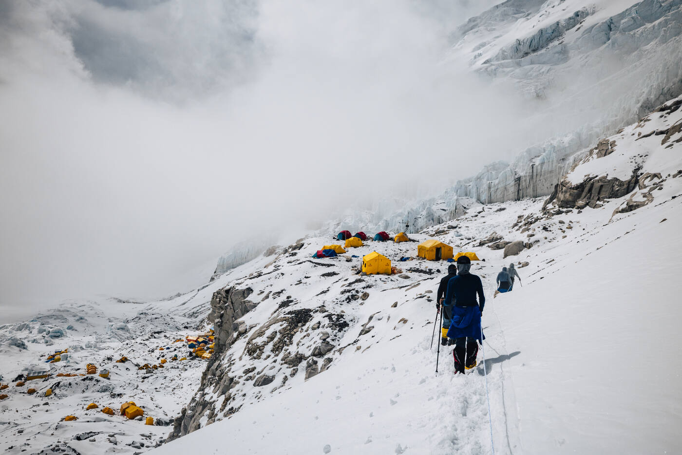 Climbers walking toward the tents of Camp 2 beneath the cloud-covered Lhotse Face