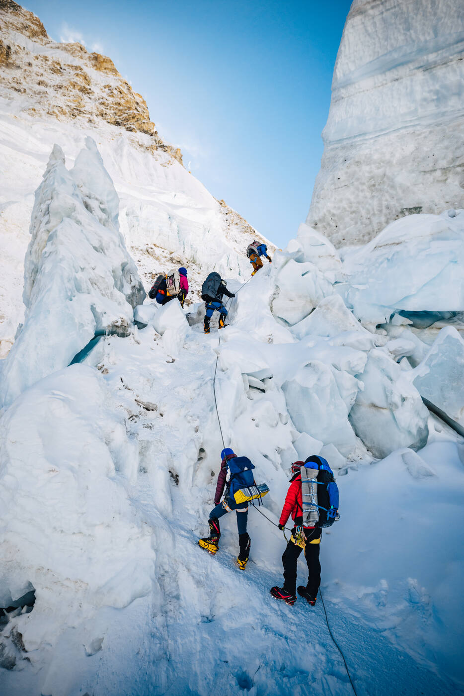 Climbers ascending on fixed ropes among towering ice blocks in the Khumbu Icefall