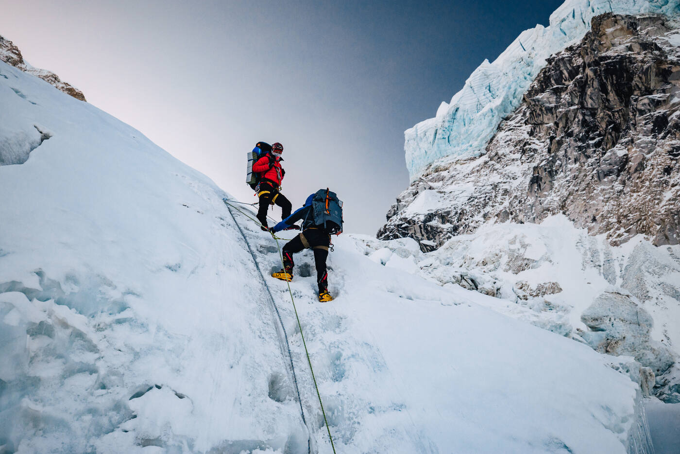 Two climbers ascending steep ice on fixed ropes with crampons in the Khumbu Icefall