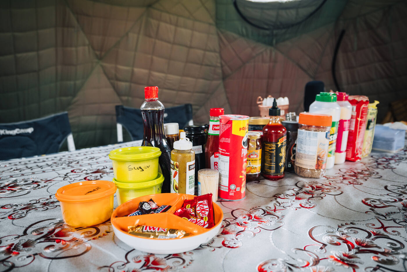 Close-up of condiments, hot sauce, and snacks on the dining tent table at Base Camp