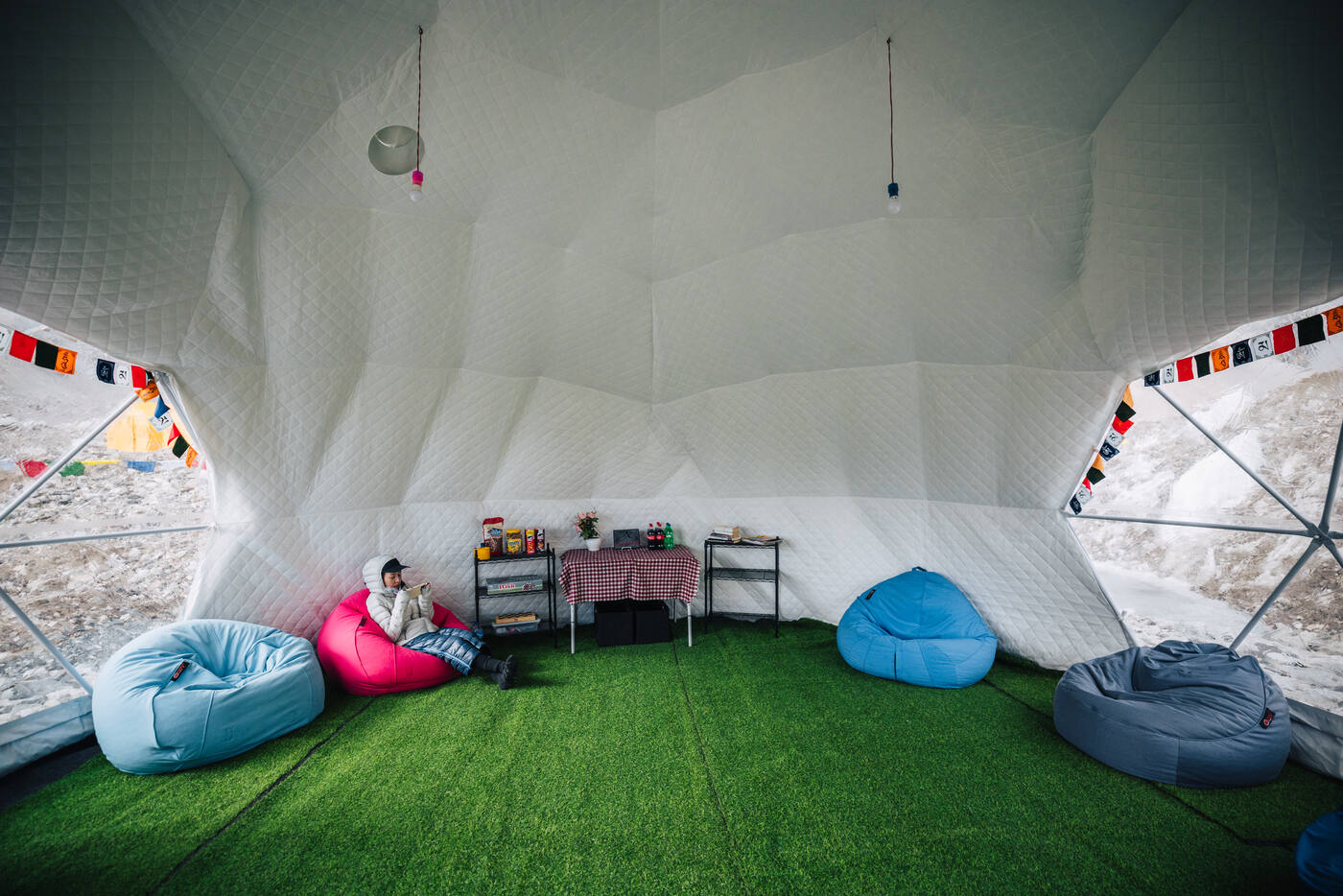 Interior of the geodesic dome tent at Everest Base Camp with bean bag chairs, artificial turf, and a snack table