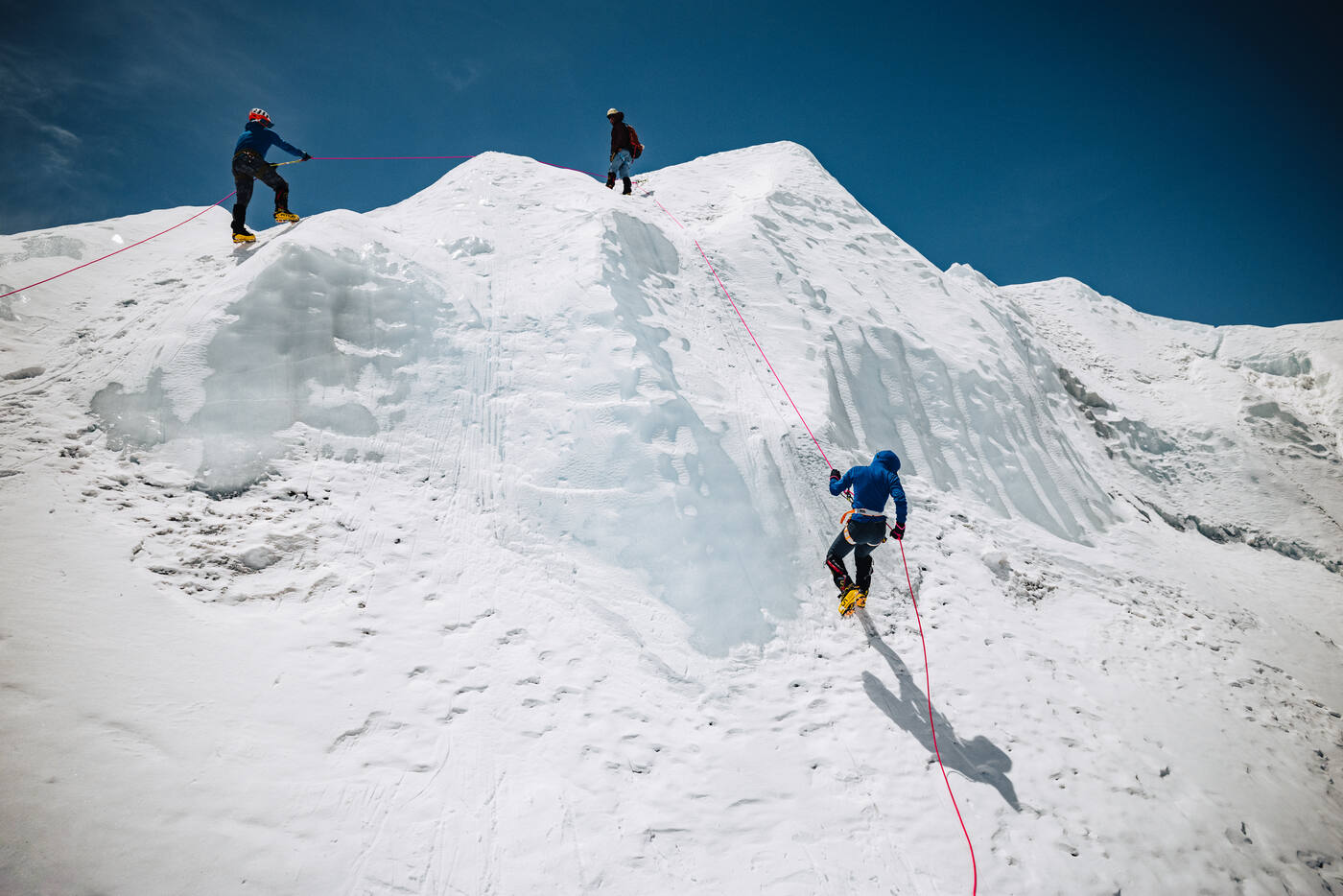 Climbers practicing ice climbing techniques on a blue ice wall at Everest Base Camp