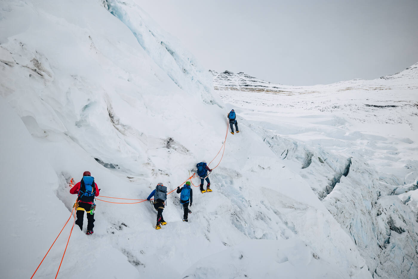Climbers on fixed ropes traversing a snow slope