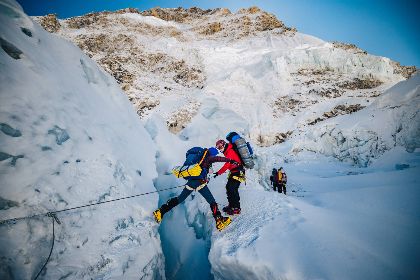 Climbers navigating fixed ropes near a crevasse in the Khumbu Icefall
