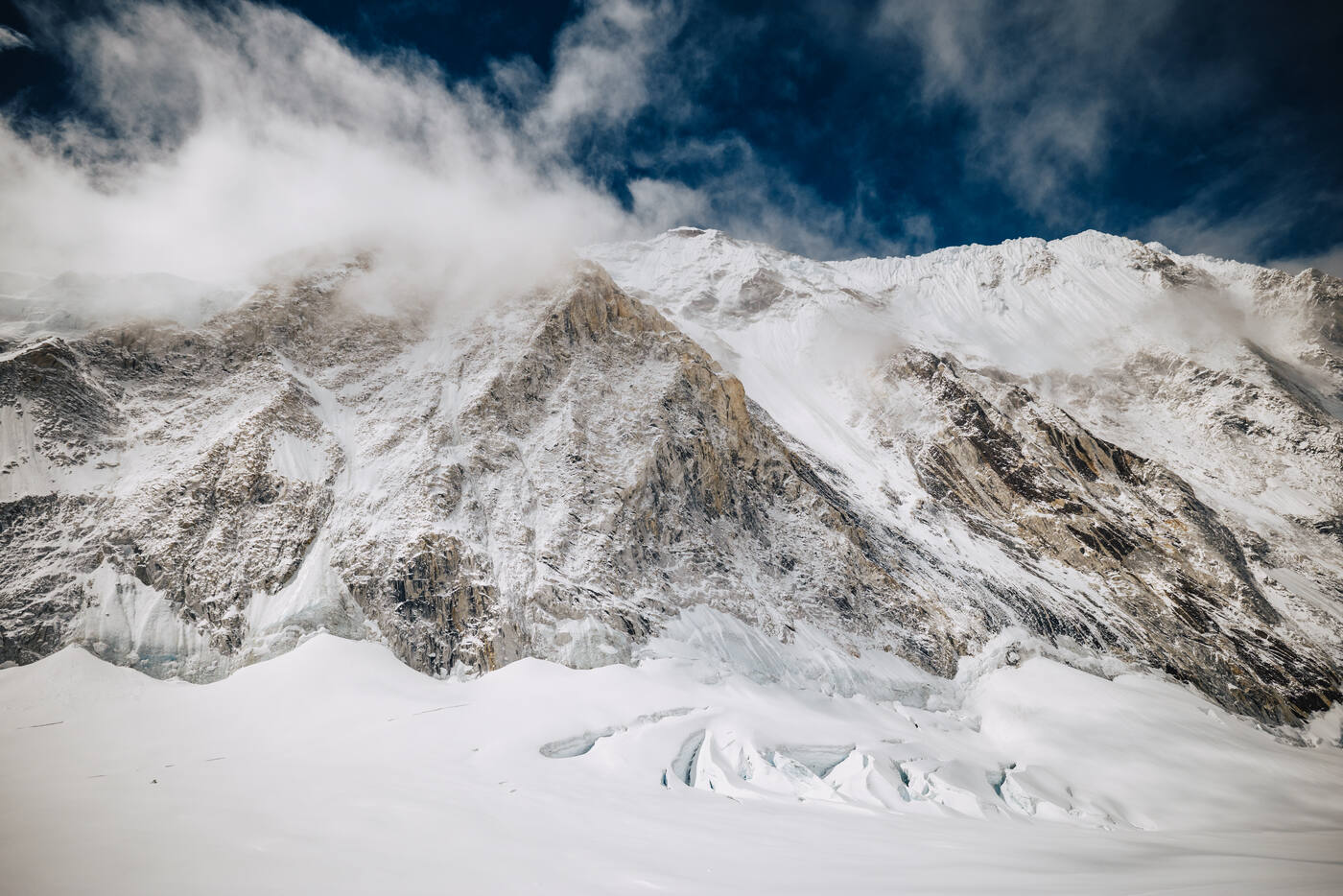 Rocky mountain wall with cloud streaming over the ridge above the glacier