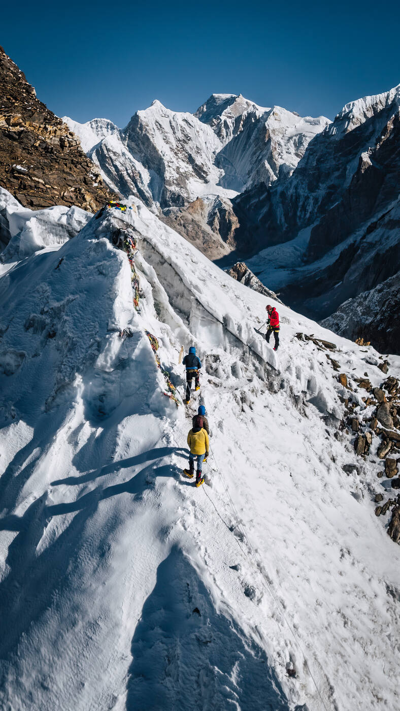 Climbers on the snow ridge of Lobuche East with peaks behind