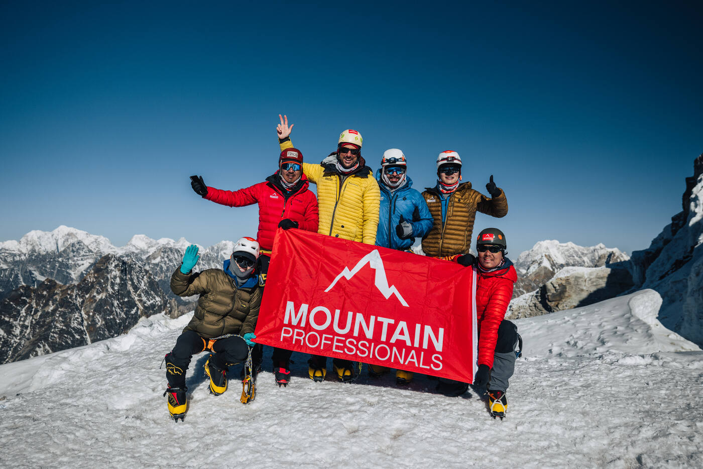The team celebrating on the summit of Lobuche East holding the red Mountain Professionals banner