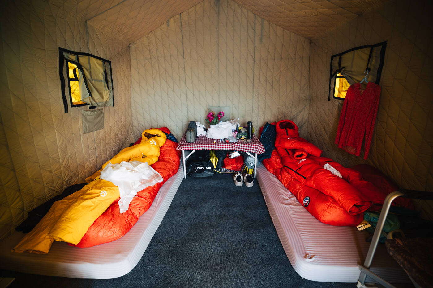 Interior of a sleeping tent at Everest Base Camp with two down sleeping bags on cots and a small table between them