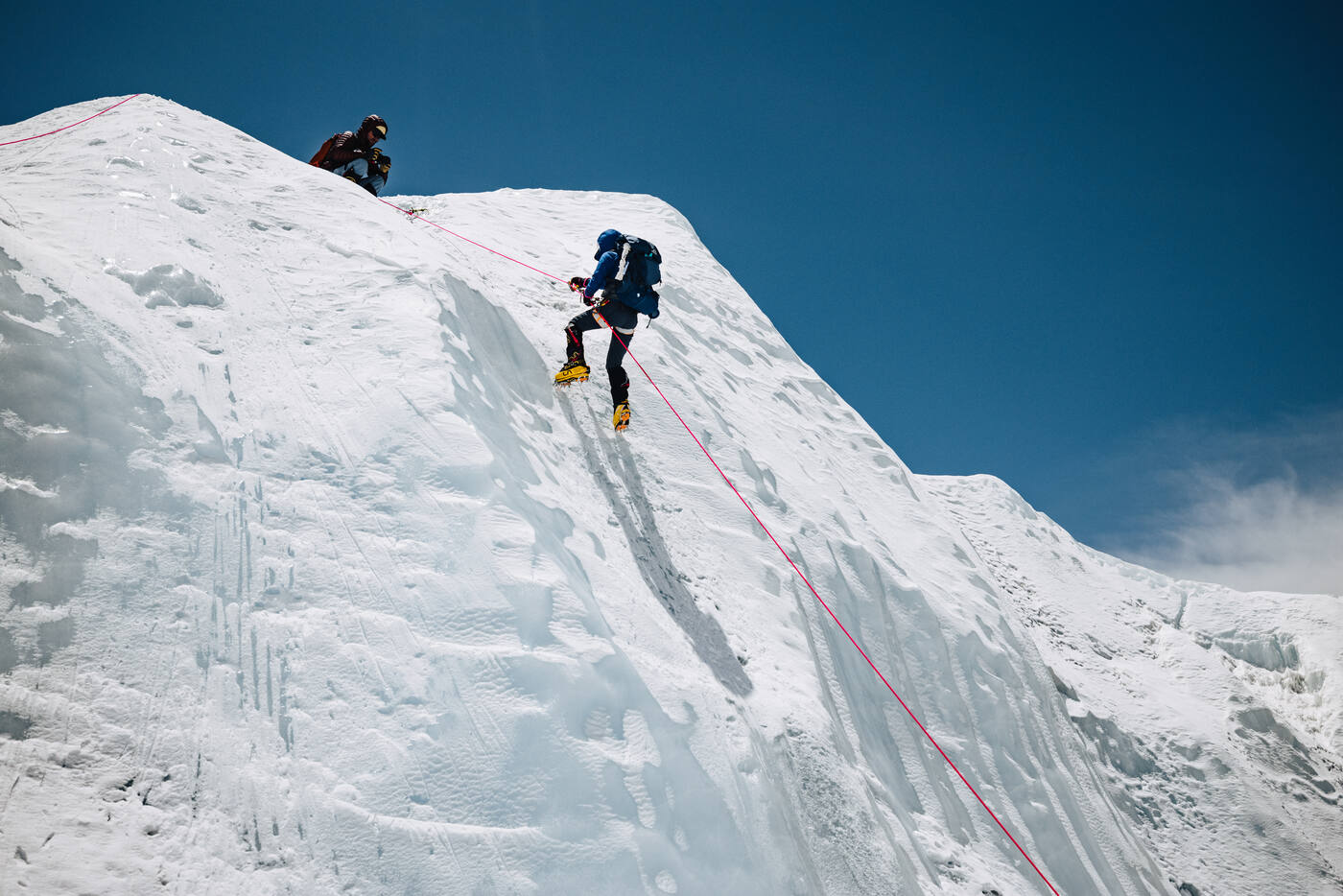 Two climbers ascending a steep ice wall on fixed ropes near the Khumbu Icefall
