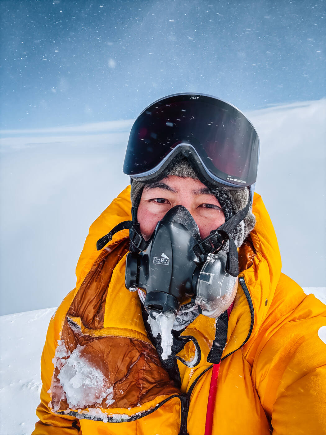 Close-up selfie of Jason wearing oxygen mask and goggles near the summit of Everest with ice on his face