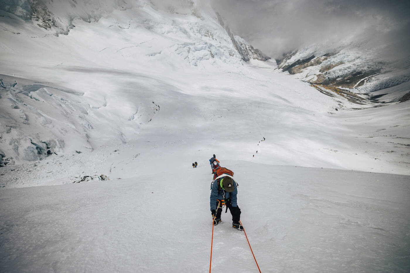 Climber ascending a steep snowy slope on fixed rope during the summit push
