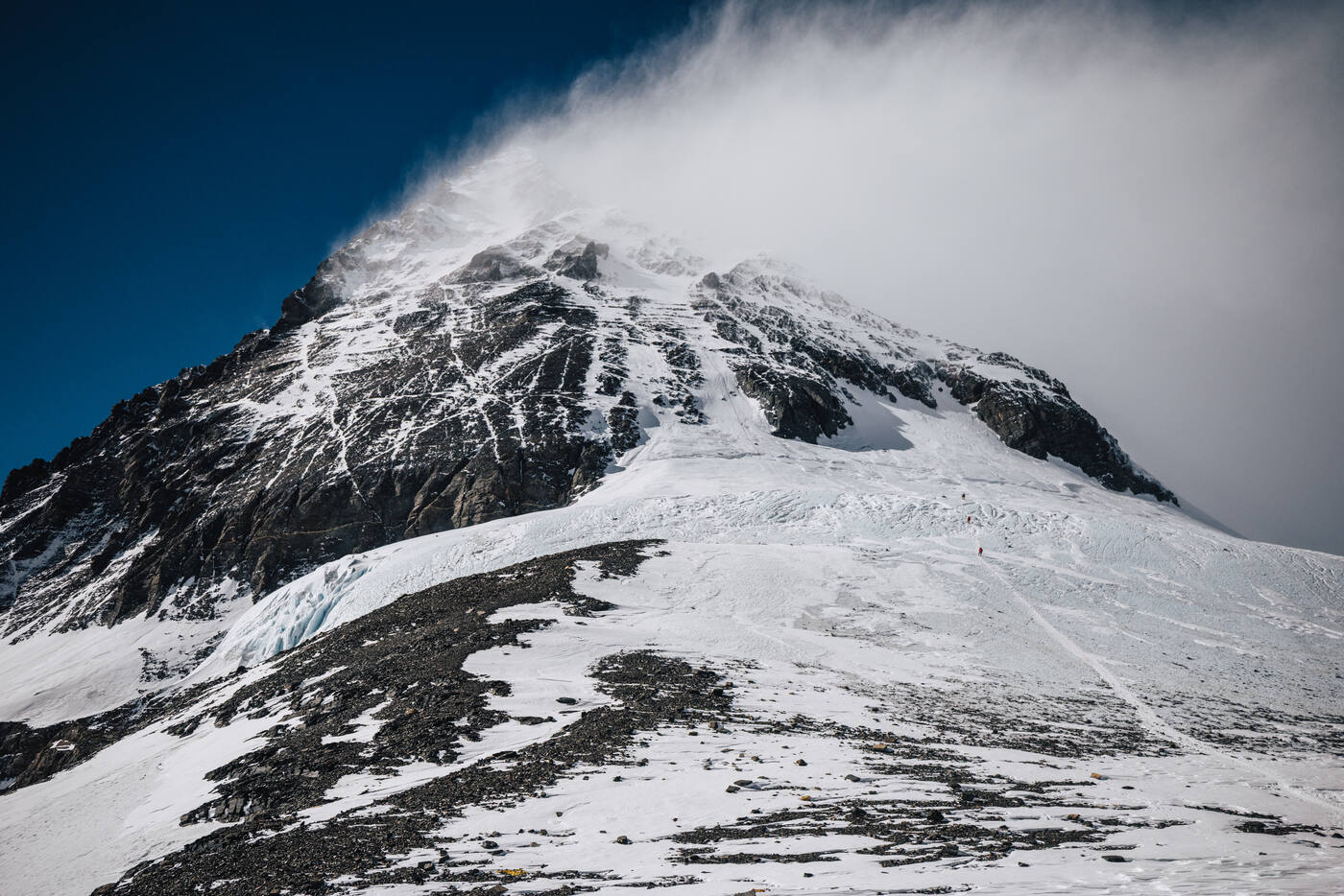 The summit pyramid of Everest with clouds streaming off the peak seen from below