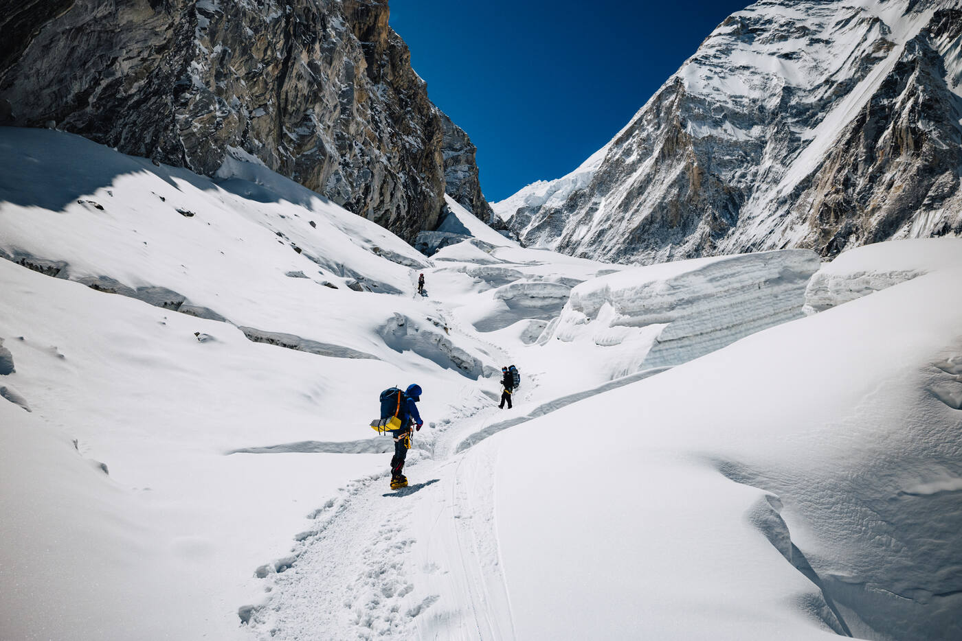 Climbers walking through the Western Cwm toward Camp 2 with steep mountain walls on both sides