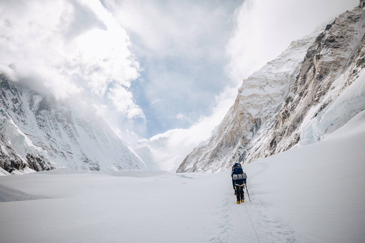 Single climber walking through the Western Cwm toward the Lhotse Face with massive mountain walls on both sides