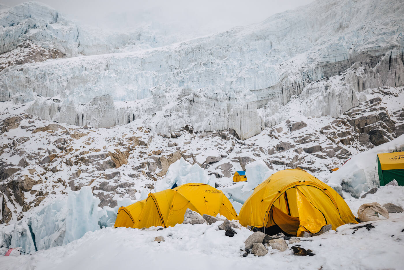 Yellow tents at a high camp below a wall of ice